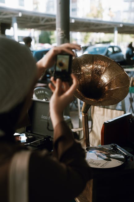 A person photographing a vintage gramophone at an outdoor antiques market in Antalya, Türkiye.