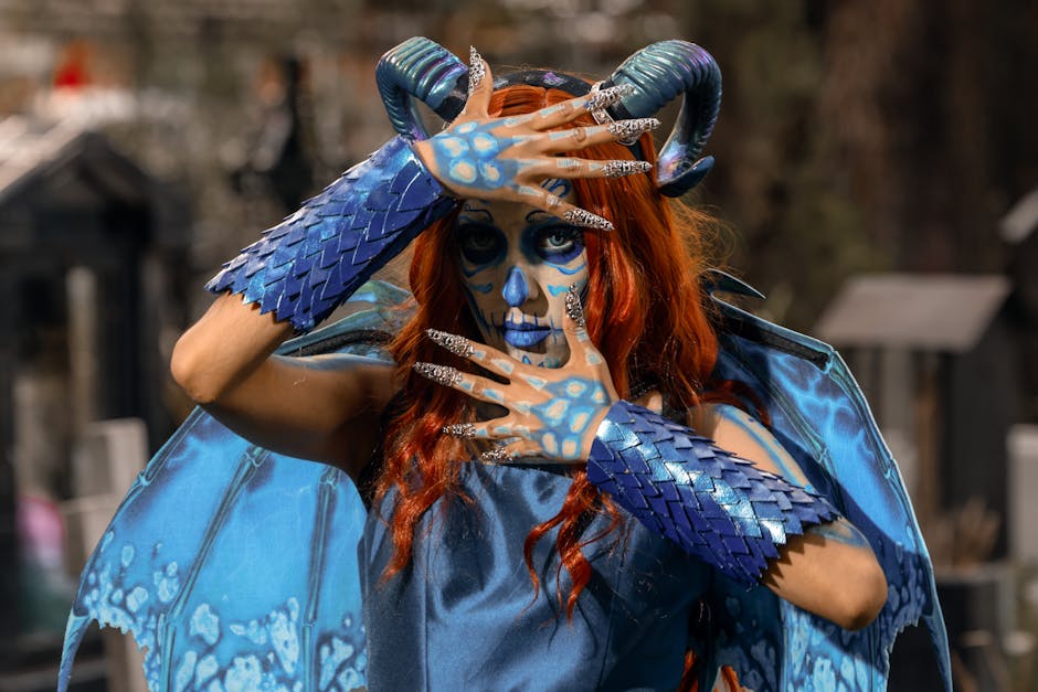 A person wearing a vibrant demon costume with intricate blue body paint, horns, and scales.