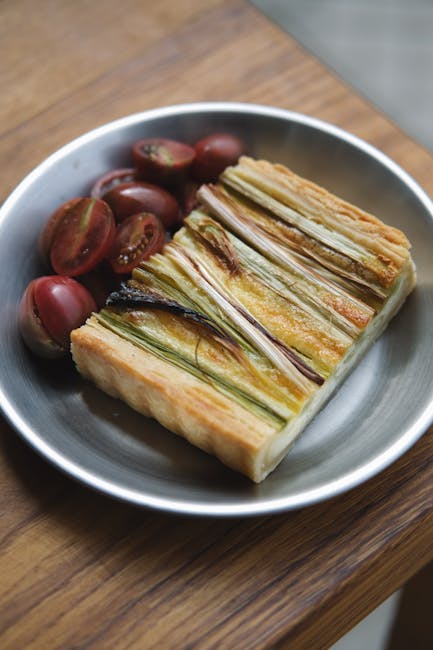 Close-up of a vegetable tart with cherry tomatoes on a wooden table.